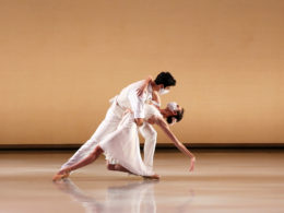 Two dancers pose on stage with masks