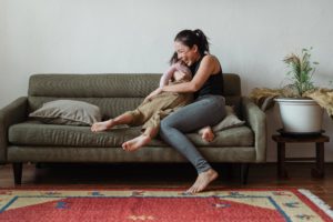 Mother and child hug, lauging embraced on a modern-style couch
