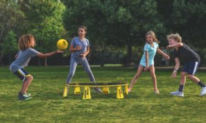 Four kids passing a ball around with a small trampoline in the middle