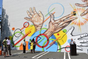 Unveiling of RBH mural, hands reaching up and out with bright colors and shape accents