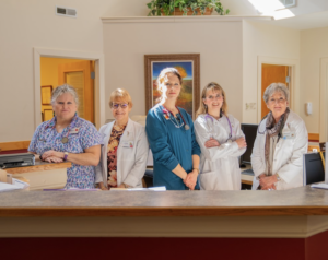 A group of five nurses standing at the front desk at Lackey Clinic.