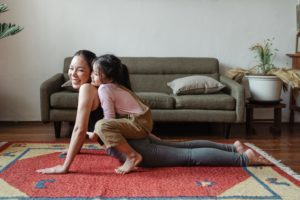 Mother and child smiling, doing yoga in floor