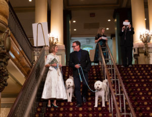 Two Fur Ball attendees walk two poodle-like dogs down stairs