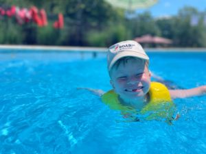Child swiming in a swimming pool with a SOAR365 hat on