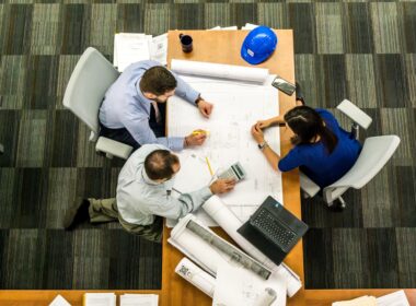 Three people sit at a table discussing business.