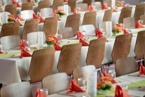 A conference set up with rows of chairs, flowers, and glassware