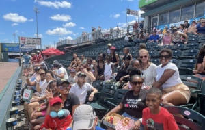 A large group of parents and their children smile at a baseball game in Richmond, VA