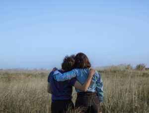 Two people embracing in front of a field