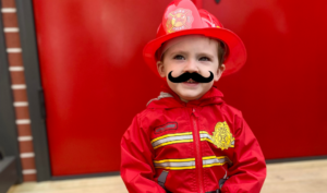 Child in firefighter costume and fake mustache.
