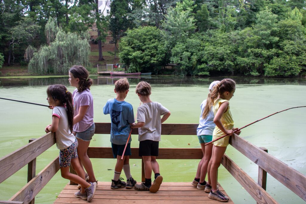 A group of 8 kids fishing on a pier at Camp Kum-Ba-Yah