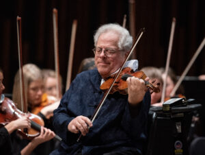 A man plays violin in a symphony.