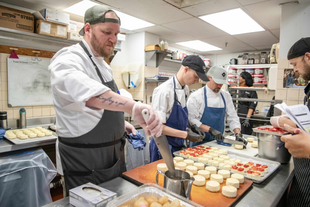 chefs in kitchen preparing a dessert