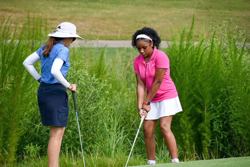 A teenager and mentor work on putting on the golf course